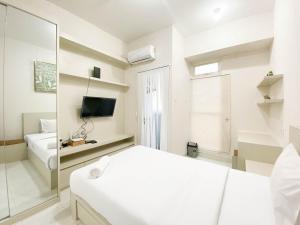 a white bedroom with a bed and a mirror at Minimalist and Homey Studio Room at Amartha View Apartment By Travelio in Semarang