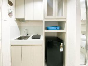 a small kitchen with a sink and a refrigerator at Minimalist and Homey Studio Room at Amartha View Apartment By Travelio in Semarang