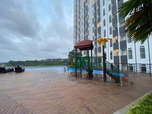 a boardwalk with a bench and an umbrella next to a building at Minimalist and Homey Studio Room at Amartha View Apartment By Travelio in Semarang