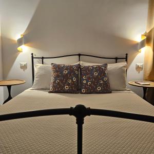 a bedroom with a bed with pillows and two tables at VOLPE E UVA Winesuites & Spa in Trani