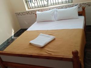 a bed with a white towel on top of it at LJ Rooms in Pākkam +4 photos
