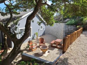 a backyard with a table and chairs and a tree at The Beach House Paradise in Jeffreys Bay