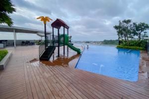 un parque infantil con un tobogán junto a una piscina en Comfortable 1BR without Living Room at Amartha View Apartment By Travelio, en Semarang