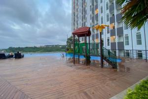 una terraza de madera con sombrilla junto a un edificio en Comfortable 1BR without Living Room at Amartha View Apartment By Travelio, en Semarang