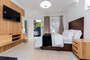 1 dormitorio con 1 cama grande y TV en ADAIA GUEST House, en Johannesburgo