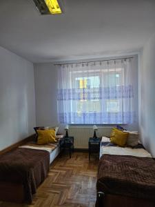 Dos camas en una habitación con ventana. en Hostel kamelarny dla seniorow z celodobowa opieka Wera, en Ząbki