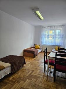 Un dormitorio con dos camas y una mesa y una ventana. en Hostel kamelarny dla seniorow z celodobowa opieka Wera, en Ząbki