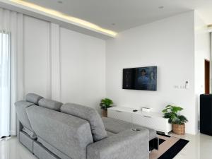 a living room with a couch and a tv on a wall at Pisingha Pool Villa Khanom in Khanom