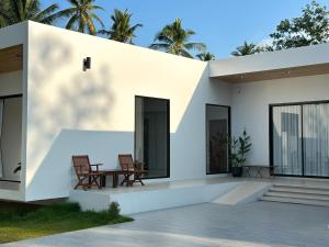 a white house with two chairs and a table at Pisingha Pool Villa Khanom in Khanom
