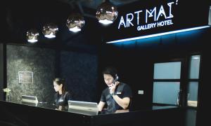 a man and a woman sitting at a desk with a computer at Art Mai Gallery Nimman Hotel Chiang Mai - SHA Plus in Chiang Mai