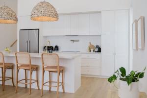 Una cocina con gabinetes blancos y taburetes de bar. en Betty at Mollymook, en Mollymook