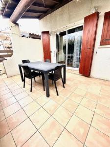 a black table and chairs on a patio at T2 cabine avec piscine collective, parking, climatisation, pour 4 personnes in Saintes-Maries-de-la-Mer