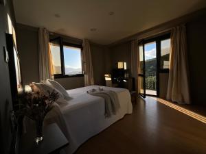 a bedroom with a bed with white sheets and windows at Hotel Don Pablo in Villasana de Mena