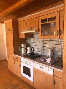 a kitchen with wooden cabinets and a stove top oven at Ferienwohnungen Gruber in Kiefersfelden +10 photos