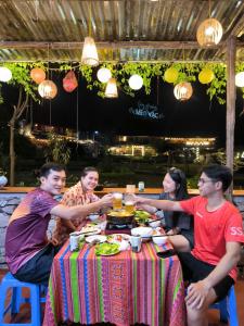 a group of people sitting around a table eating at Xúa Vừ Homestay in Mèo Vạc +82 photos