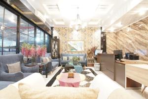 a lobby with couches and tables and a wall of windows at Tasqya Costel syariah in Parit