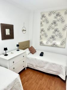 ein Schlafzimmer mit zwei Betten und einer Kommode in der Unterkunft 10 minutos centro Sevilla, moderno y con parking gratis in Sevilla