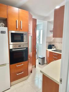 eine Küche mit Holzschränken und einem Herd mit Backofen in der Unterkunft 10 minutos centro Sevilla, moderno y con parking gratis in Sevilla