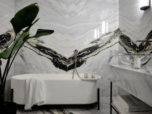 a bathroom with a white tub and a marble wall at Argini Syros in Ermoupoli