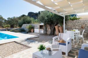 a patio with a pool and a table and chairs at Villa Kalathos Dream Galazio in Kalathos
