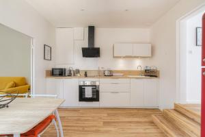 a kitchen with white cabinets and a wooden floor at Maison avec terrasse proche Lyon in Rillieux +17 photos