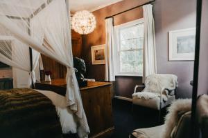 a bedroom with a bed and a window and a chandelier at Klein Geluk Cottage in Nieu-Bethesda