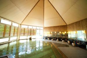 a large swimming pool in a large building with windows at Kijima Kogen Hotel in Beppu +30 photos