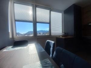 シュコダルにあるApartment Kraja Shkoderのテーブルと椅子2脚、窓2つが備わる客室です。