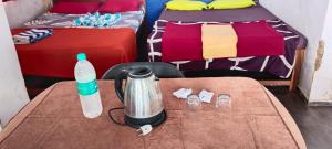 a room with two beds and a table with a water bottle at Red Rock Arambol Beach in Arambol
