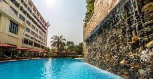 a swimming pool in front of a building at Rose Garden Hotel in Yangon