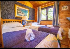a bedroom with two beds in a log cabin at Five Waterings - Puddock Farm Romney Marsh in Brookland