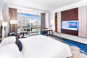 a bedroom with a large bed and a flat screen tv at Beach Rotana - Abu Dhabi in Abu Dhabi