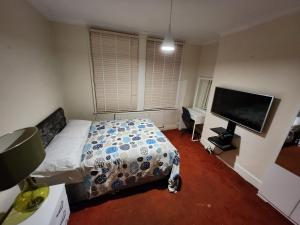 a bedroom with a bed and a flat screen tv at Home away from Home in Thornton Heath