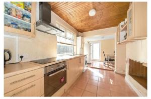 a kitchen with wooden cabinets and a table in it at Home away from Home in Thornton Heath