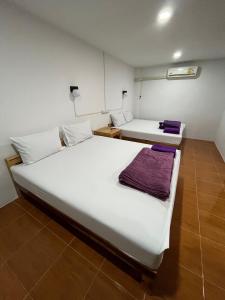 two beds in a room with white sheets at บ้านใบไม้โฮมสเตย์แอนด์รีสอร์ท in Surat Thani
