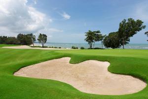 a view of a golf course with the ocean in the background at Ahnaf Homestay Desaru in Bandar Penawar