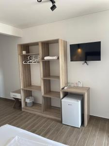 a room with wooden shelves and a tv on a wall at Costa Varda Apartments in Mourteri