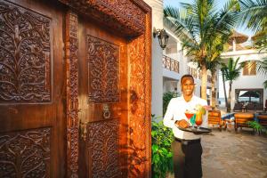 a man standing in front of a door with a plate of food at Karibu Beach Resort - Adults Only in Pongwe