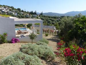 a house with a view of a garden with flowers at Villa Gianna Maria in Paleros