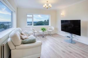 un salon avec un canapé et une télévision à écran plat dans l'établissement Longview - 4 Bedroom Holiday Home - Pembroke Dock, à Pembroke Dock
