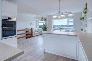 une cuisine avec des armoires blanches et un salon dans l'établissement Longview - 4 Bedroom Holiday Home - Pembroke Dock, à Pembroke Dock