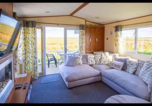a living room with a couch and a television at MP503 - Camber Sands Holiday Park - Sleeps 8 - Large Gated Decking - Amazing views in Camber