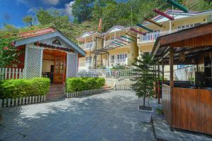 a group of houses with a building with a tree in front at Pax Hotel Rock Villa Swimming Pool Available Dalhousie in Dalhousie