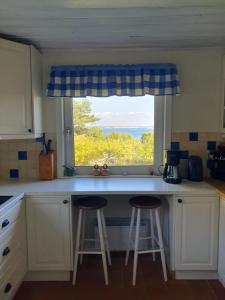 a kitchen with two bar stools in front of a window at Boende på SydKoster med havsutsikt och nära till bryggor in Strömstad