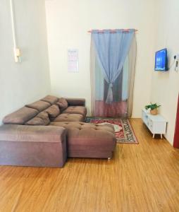 a living room with a brown couch in a room at Rayyan homestay in Kampong Dalam Ru