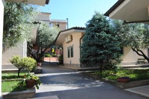 un cortile con un edificio, alberi e una strada di Hotel Tecla a Fonte Nuova