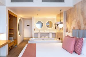 a bedroom with a large white bed and a tub at Hotel Cristina by Tigotan Las Palmas - Adults Only in Las Palmas de Gran Canaria
