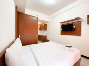 a bedroom with a white bed and a tv at Cozy Stay Studio Cordova Edupartment Semarang Apartment By Travelio in Semarang +4 photos