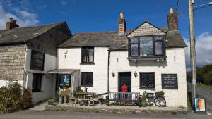 以撒港The Cornish Arms Inn的前面有一张桌子和长凳的白色建筑
