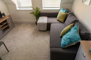 a living room with a gray couch with pillows at Beautiful town centre apartment in Huntingdon